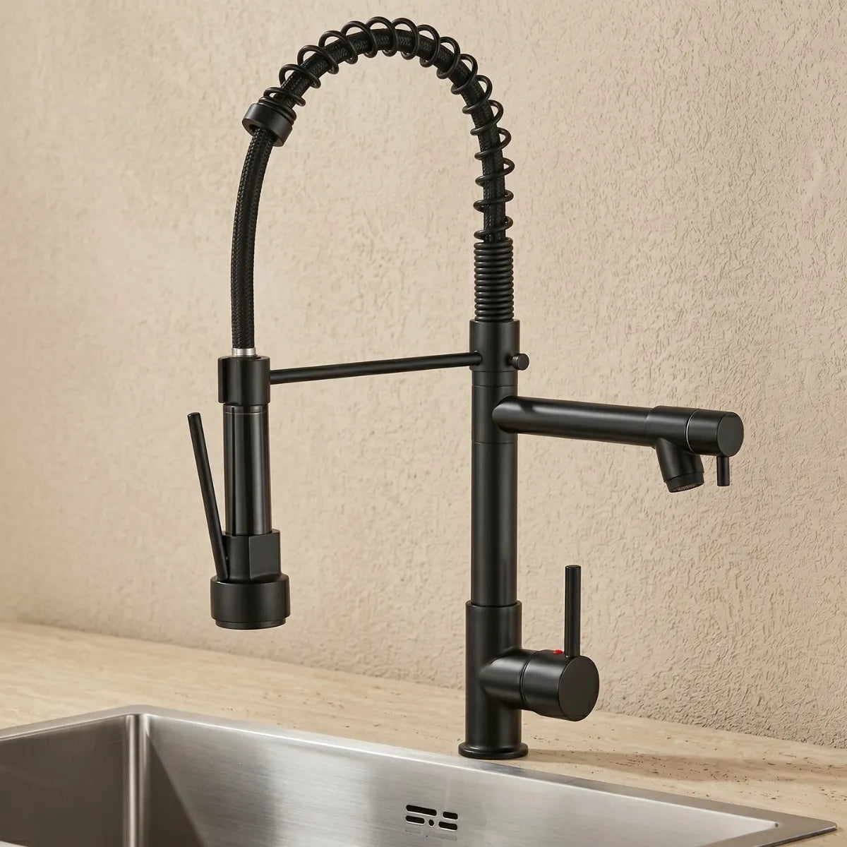 Torneira para cozinha gourmet preta matte com mola industrial e bica dupla articulada, instalada sobre cuba de inox embutida em bancada neutra, vista frontal.