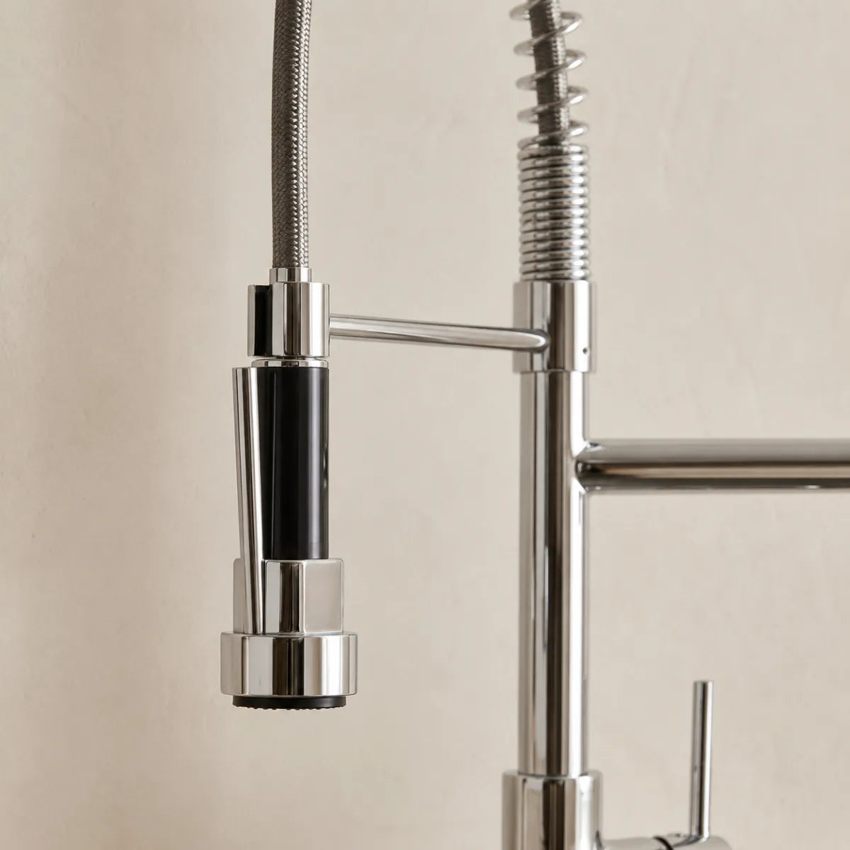 Detalhe da ducha da torneira para cozinha flexível cromada, com corpo bicolor cromo e preto, bocal multifunção e mola espiral em acabamento polido.