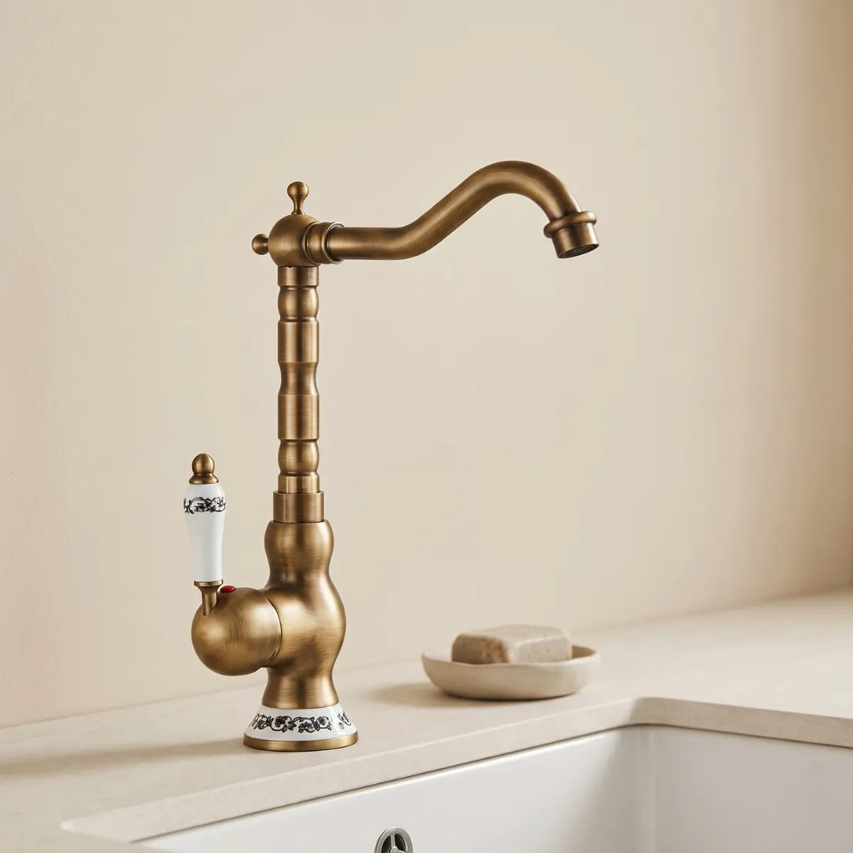 Imagem de uma torneira para cozinha de latão em modelo clássico na cor dourado envelhecido em pia de cozinha bege