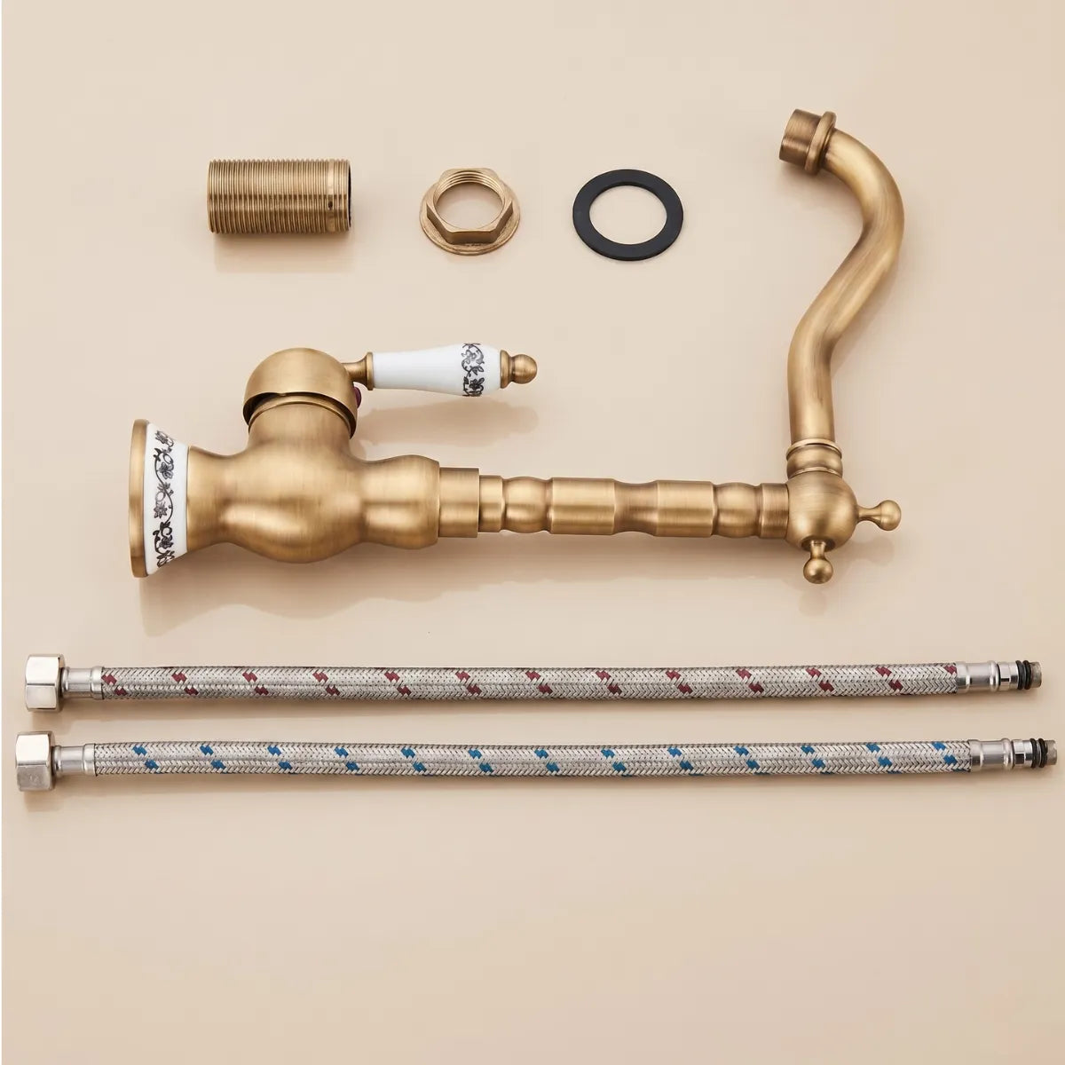 Imagem de uma torneira para cozinha de latão em modelo clássico na cor dourado envelhecido disposta em fundo bege com acessórios