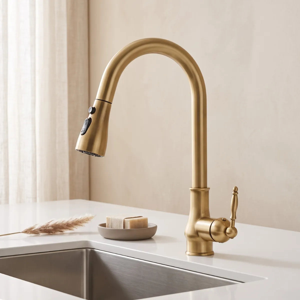 Torneira para cozinha vintage dourada escovada com bica alta e ducha retrátil sobre pia de inox em bancada branca minimalista